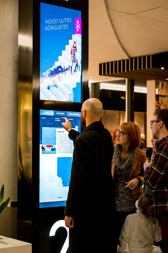 A man using an interactive digital signage screen in a mall