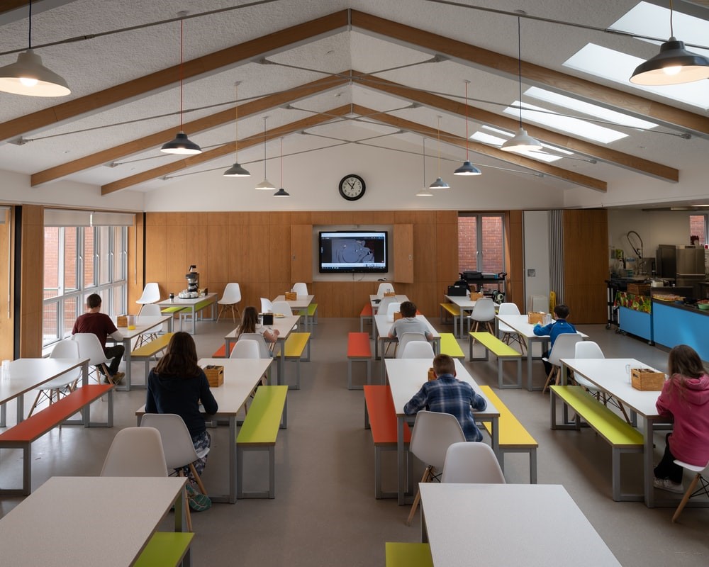 Students social distancing in a classroom with a digital display in the front.